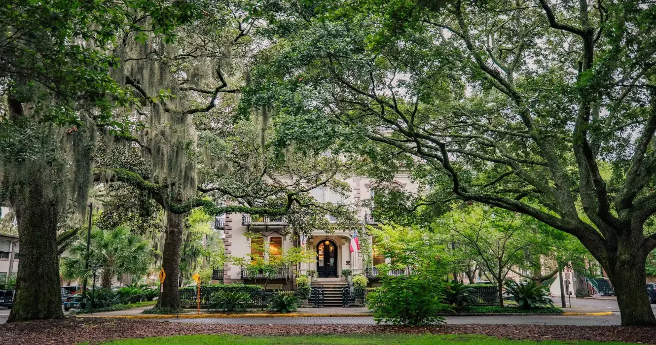 Praça arborizada em Savannah com bancos de ferro e casas históricas ao redor