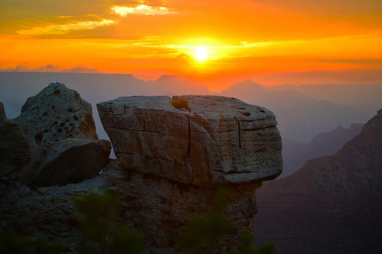 Vista panorâmica do Grand Canyon ao amanhecer com tons alaranjados nas formações rochosas