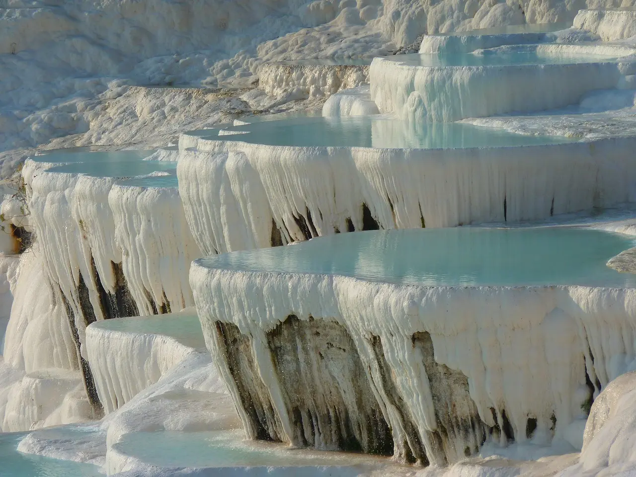 Terraços brancos de travertino com águas azuis em Pamukkale
