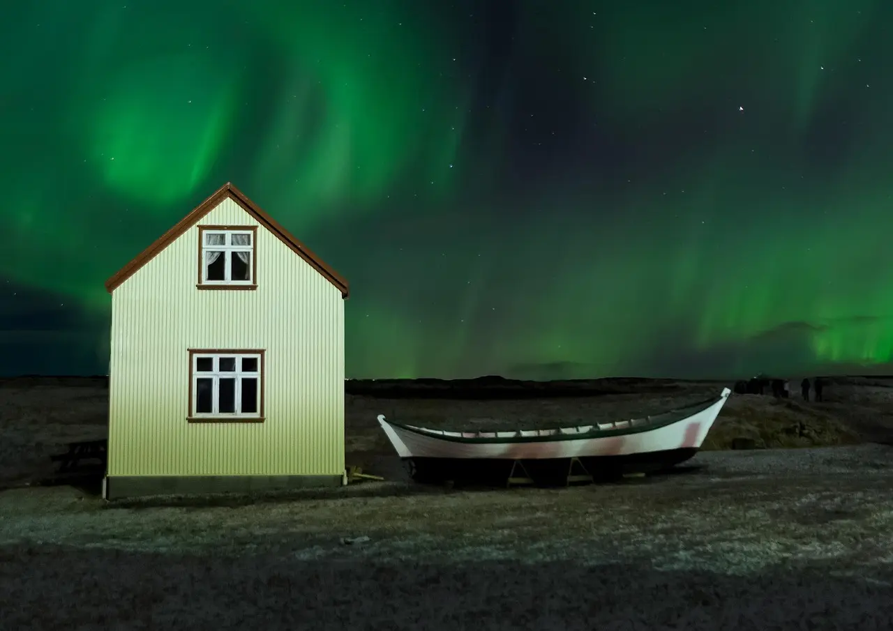 Aurora boreal sobre paisagem gelada com cabana isolada na Islândia