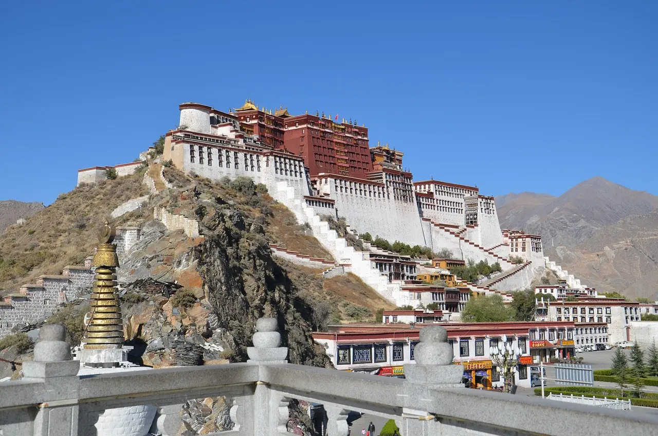 Potala Palace em Lhasa, Tibete, com céu azul intenso e montanhas ao fundo.