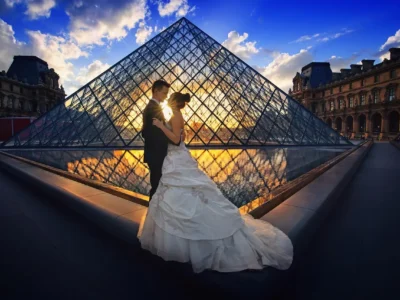 Casal caminhando de mãos dadas por uma ponte antiga em Paris ao pôr do sol